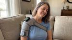 Woman relaxing on couch wearing SootheThera on her right shoulder